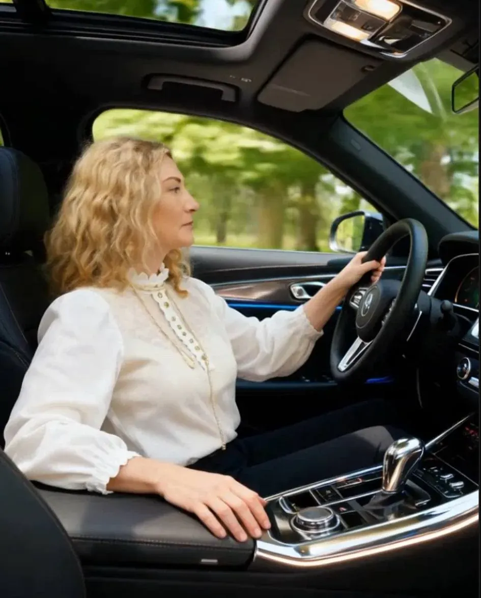 Woman driving a car with hands on the steering wheel, seen from inside the vehicle Woman driving a car with hands on the steering wheel, seen from inside the vehicle